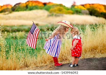 group of two happy adorable little kid girls smiling and waving American flag outside, his dress with strip and stars, cowboy hat. Smiling child celebrating 4th july - Independence Day