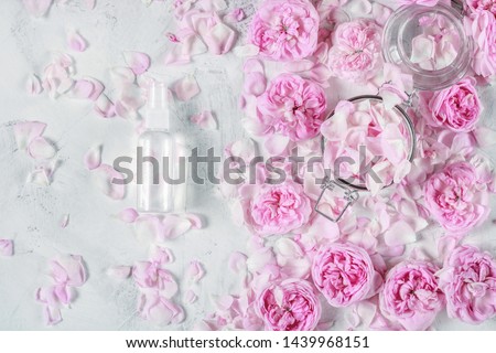water from roses for beauty and spa care with roses and rose petals on the background