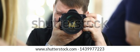 A male photographer holds camera in his hand concept. The self-portrait is reflected in the mirror.