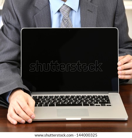 Young businessman with laptop computer facing on his workplace