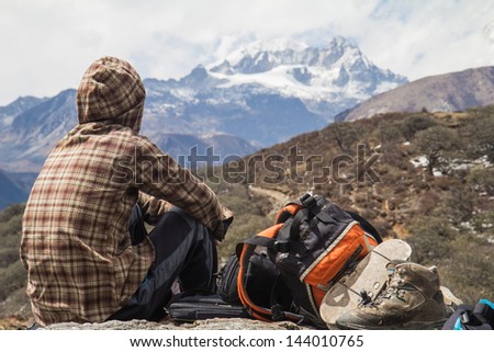 A man of trekking group rest on stone and see snow mountain in Geochala trail trekking  to Kanchenjunga ,  Sikkim India