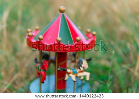 Vintage musical carousel toy in garden. Wooden flying horses music box. Dreamy childhood objects.