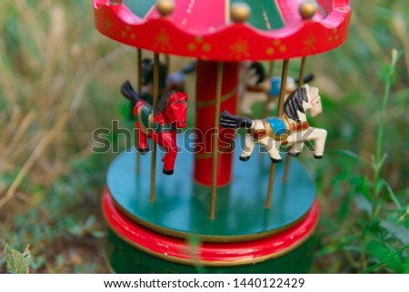 Vintage musical carousel toy in garden. Wooden flying horses music box. Dreamy childhood objects.