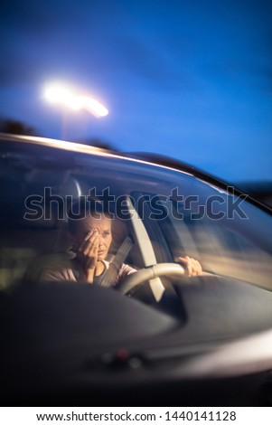 Young female driver at the wheel of her car, super tired, falling asleep while driving in a potentially dangerous situation - Road safety concept Royalty-Free Stock Photo #1440141128