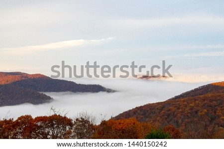 Aerial view of the Shenandoah Valley in bright autumn colors and the Appalachian mountains engulfed in clouds