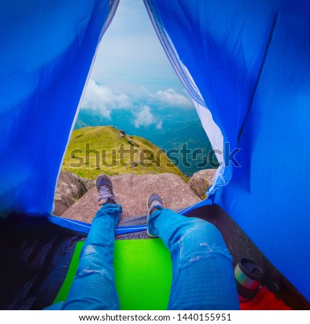 Close up of young man while enjoying the view of mountain range with blue sky and cloudy sky background, View from inside a blue tent - Image