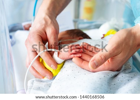 Fathers hand close-up with sick newborn child Royalty-Free Stock Photo #1440168506
