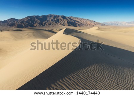 Early Morning Sunlight Over Sand Dunes And Mountains At Mesquite flat dunes, Death Valley National Park, California USA Stovepipe Wells sand dunes, very nice structures in sand Beautiful background