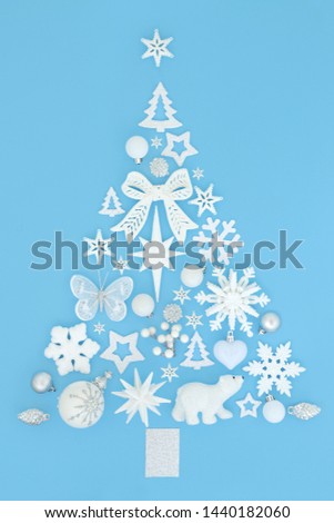 Abstract Christmas tree decoration with a large collection of white and silver baubles on pastel blue background. Traditional theme with symbols for the festive season.