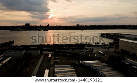 Aerial shot of a gold & orange sunset, over the Hudson River in New York with New Jersey in the background and a few boats in the calm waters