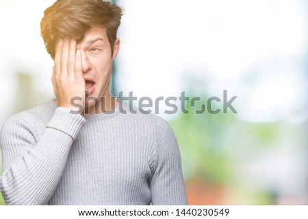 Young handsome man wearing winter sweater over isolated background Yawning tired covering half face, eye and mouth with hand. Face hurts in pain.