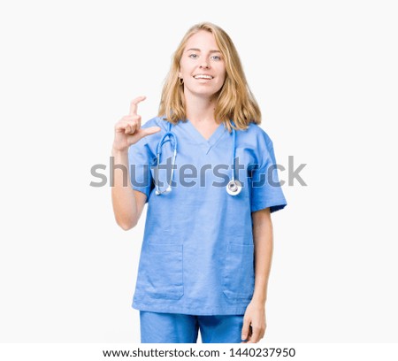 Beautiful young doctor woman wearing medical uniform over isolated background smiling and confident gesturing with hand doing size sign with fingers while looking and the camera. Measure concept.