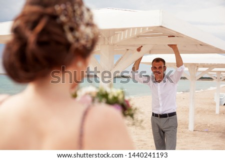rear view of the woman look to thу groom. closeup of wedding dress. the man sit in the beach