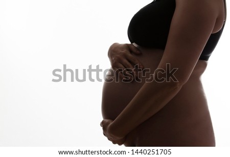 Pregnant woman with a baby bump silhouetted on a white background