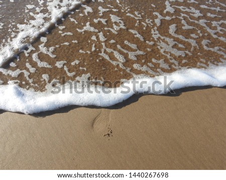 White bubbles of wave crash the sandy beach , for background