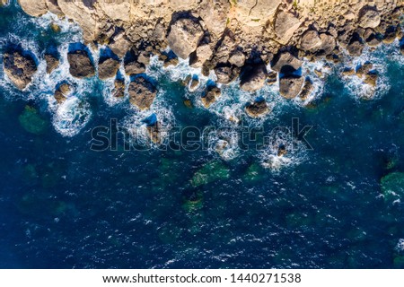 Sea background. Aerial top view. Copy space at blue sea backdrop. Seashore with stones and clear blue water. Clean environment.