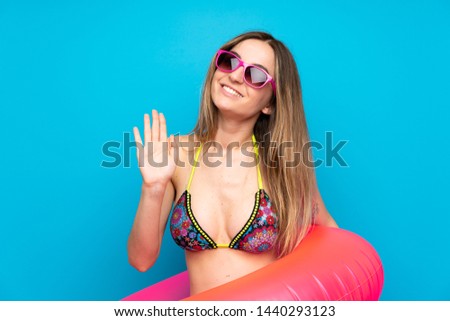 Young woman in bikini in summer holidays saluting with hand with happy expression