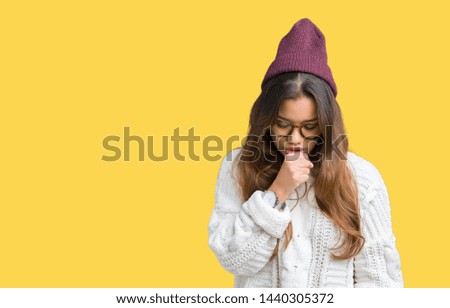 Young beautiful brunette hipster woman wearing glasses and winter hat over isolated background feeling unwell and coughing as symptom for cold or bronchitis. Healthcare concept.