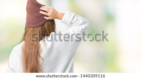 Young beautiful brunette hipster woman wearing glasses and winter hat over isolated background Backwards thinking about doubt with hand on head