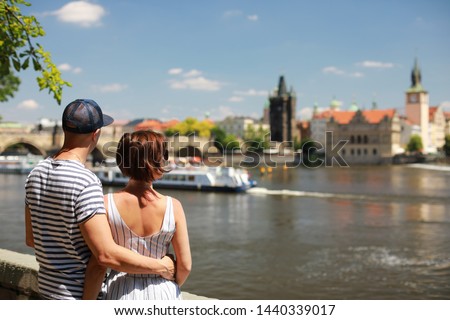 Man and woman siting on quay near river Vltava with beautiful Charles bridge view in sunny day. Royalty-Free Stock Photo #1440339017