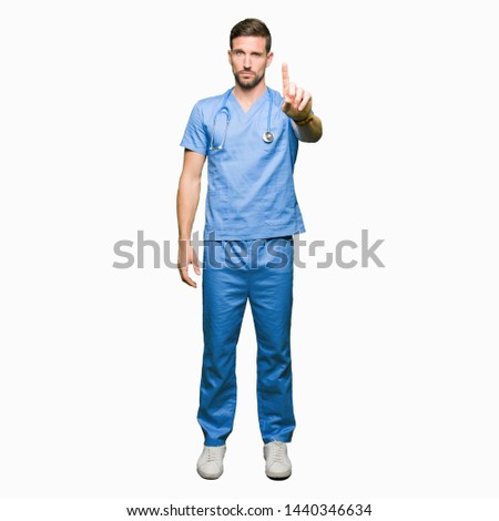 Handsome doctor man wearing medical uniform over isolated background Pointing with finger up and angry expression