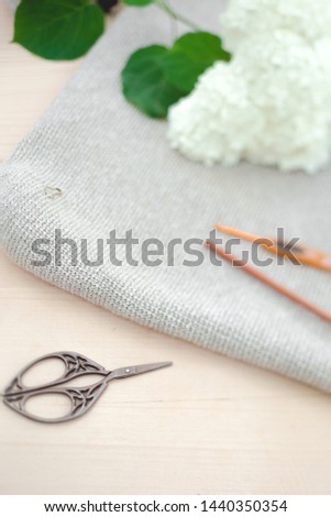 Knitted bag from a light gray cotton yarn, thread for knitting and knitting acsessories closeup.