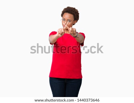 Beautiful young african american woman wearing glasses over isolated background Rejection expression crossing fingers doing negative sign