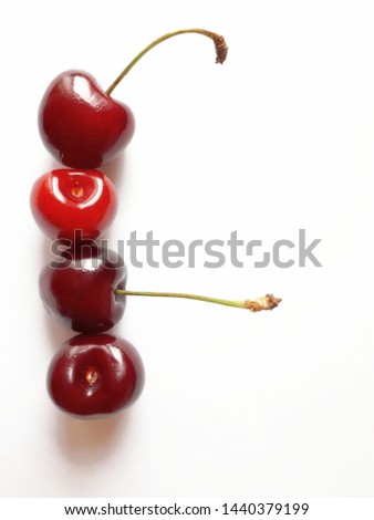 Four cherries in a row on a white background with space for text, top view