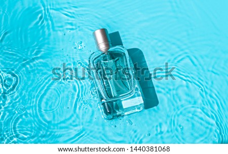 Transparent glass cosmetic perfume bottle in the blue water . Top view Royalty-Free Stock Photo #1440381068