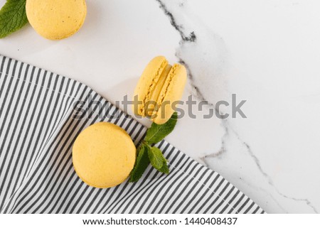 French macaroons isolated. Selective focus. Beautiful yellow macaroons with mint in striped napkin on marble background. Stylish arrangement sweet. Flat lay, top view. Macro photo. With copy space.