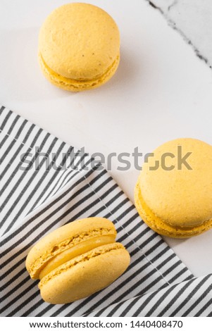 French macaroons isolated. Selective focus. Beautiful yellow macaroons in striped napkin on marble background. Stylish arrangement sweet. Flat lay, top view. Macro photo.