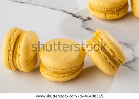 French macaroons isolated. Selective focus. Beautiful yellow macaroons on marble background. Stylish arrangement sweet. Flat lay, top view. Macro photo. With copy space.