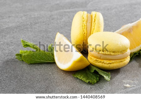 French macaroons isolated. Selective focus. Beautiful yellow macaroons with lemon and mint on gray stone background. Stylish arrangement sweet. Flat lay, top view. Macro photo.