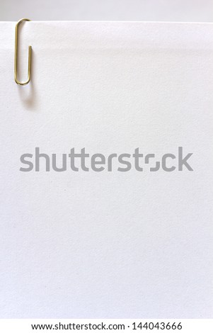 A metal paper clip and paper on white background