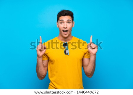 Handsome man over blue background pointing up a great idea