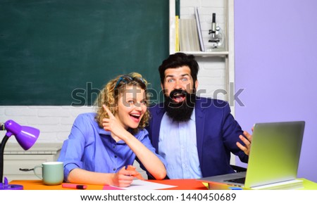 Happy female teacher with male student over green chalkboard background. Students couple studying in university. Portrait two creative students in classroom. Students and tutoring education concept.