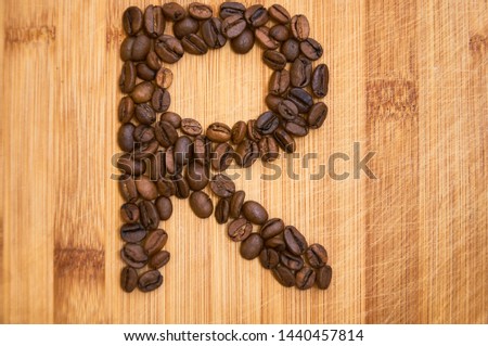 Alphabet letter R made from roasted coffee beans, 3D rendering on wooden table background