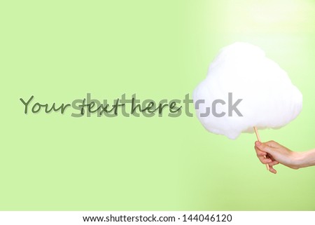 Hand holding stick with cotton candy, on color background