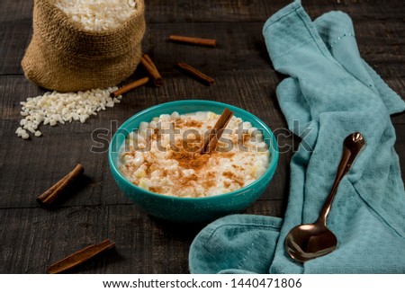 typical brazilian dish hominy canjica with cinnamon in blue pot in dark wood.
