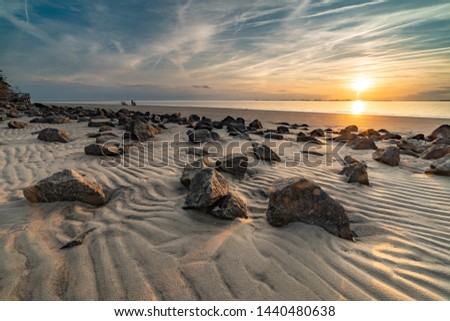 Stunning clouds cover the sky during sunset at Jekyll Island, GA showing the beautiful beach stones. Royalty-Free Stock Photo #1440480638