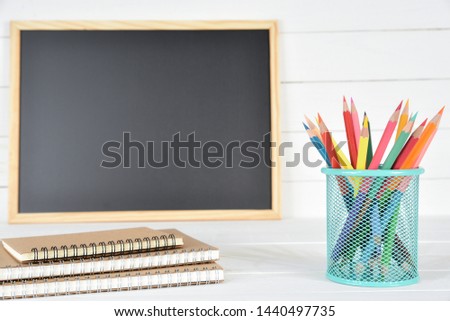School supplies on black board and white wooden background. Education or Back to school concept.