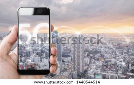 Hand using mobile smart phone, and wireless network connection technology in the city, with 5g internet networking