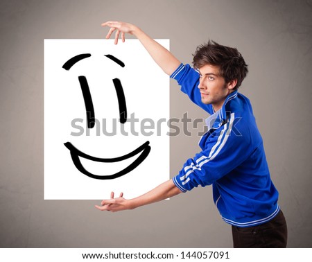 Handsome young boy holding smiley face drawing