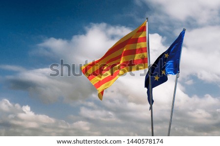 Catalonia and European Union relations - two flags waving in the wind, isolated at sky background with clouds.