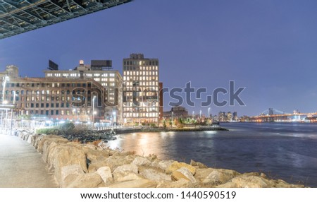 View of Brooklyn buildings from under Manhattan Nridge at night. Williamsburg Bridge on background.