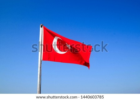 Turkish flag waving on the flagpole in the wind against the blue sky