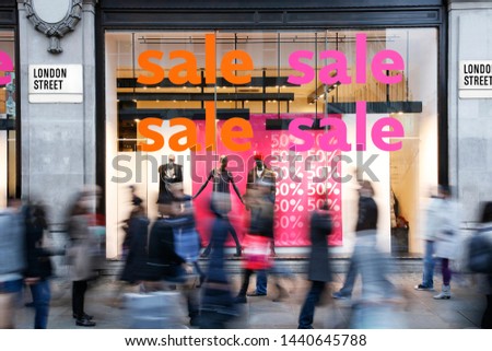 Sale signs in shop window at London's shopping street, motion blurred people present