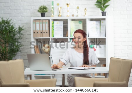 Confident woman doctor sitting at the table in her office and smiling at camera. healthcare concept.