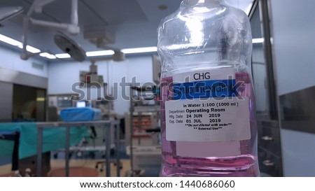 Chlorhexidine gluconate (CHG) is an antiseptic used for skin disinfection in surgery, cleaning surgical wound, sterile medical instrument to prevent infection. Blurred background of operating room. Royalty-Free Stock Photo #1440686060