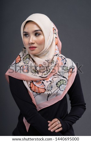 Beautiful female model wearing black color shirt with hijab, a modern lifestyle outfit  for Muslim woman isolated over grey background. Studio hijab fashion and beauty concept